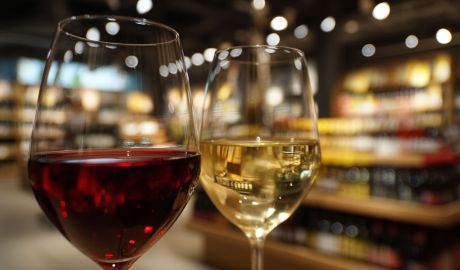 Ett glass rött och ett glas vitt vin framför Systembolaget butik